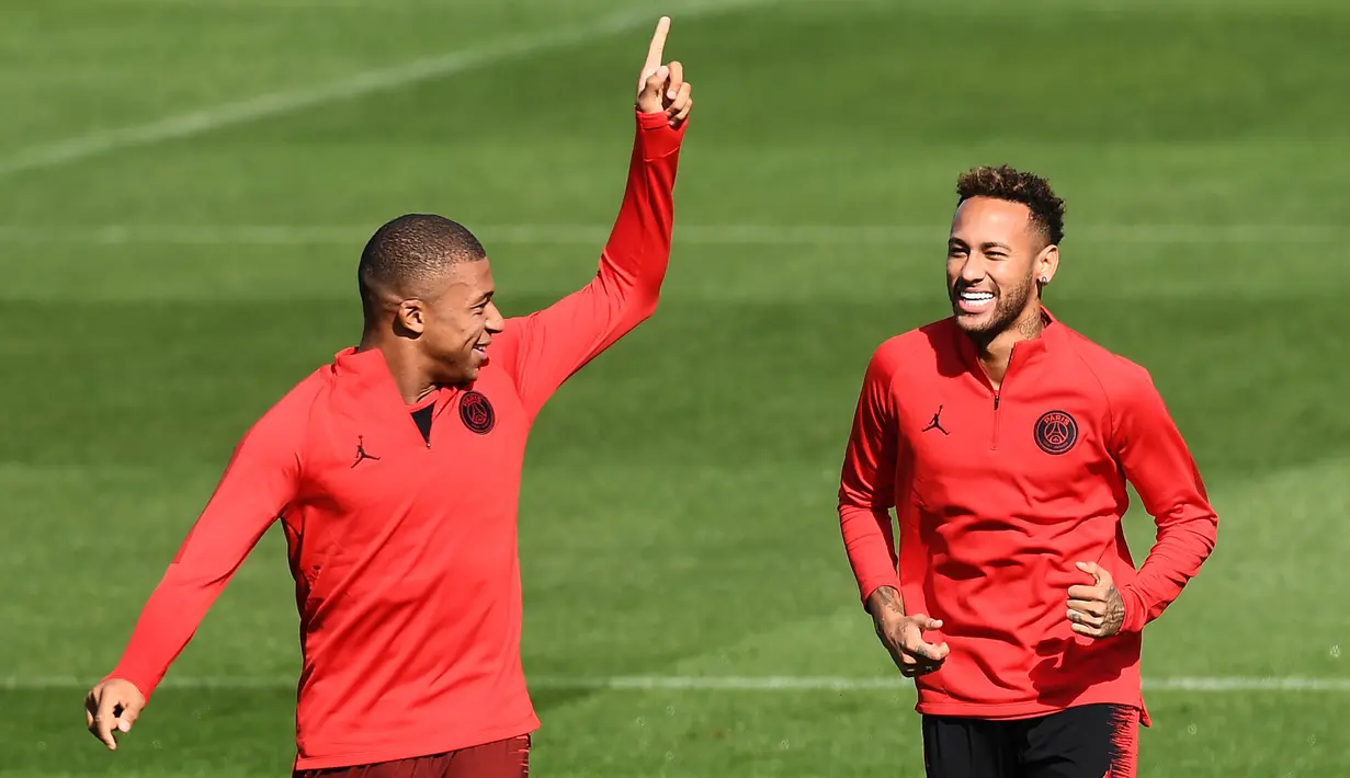 Pemain Paris Saint-Germain (PSG), Neymar (kanan) berbincang dengan Kylian Mbappe (kiri) saat sesi latihan di Paris Barat, Prancis, Senin (17/9). PSG akan menghadapi Liverpool di Liga Champions pada 19 September 2018. (Anne-Christine POUJOULAT/AFP)