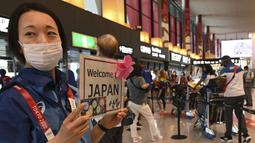 Seorang relawan menyambut delegasi Olimpiade di Bandara Internasional Narita, Prefektur Chiba pada 20 Juli 2021 untuk mengikuti Olimpiade Tokyo 2020 mendatang. (AFP/Kazuhiro Nogi)