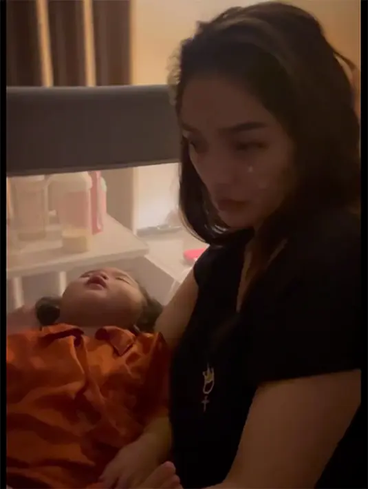 Muka lelah begitu terlihat dari penyanyi dan pemeran itu. Sedangkan putrinya yang sedang sakit tidur pulas dalam pangkuannya. [Instagram/krisjianabah]