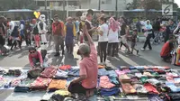 Warga melintasi lapak PKL saat car free day di MH Thamrin, Jakarta, Minggu (8/9/2019). Penutupan sebagian jalan akibat proyek revitalisasi trotoar membuat para PKL menggelar lapak hingga ke badan jalan sehingga menyebabkan aktivitas olahraga warga terhambat. (merdeka.com/Iqbal S. Nugroho)