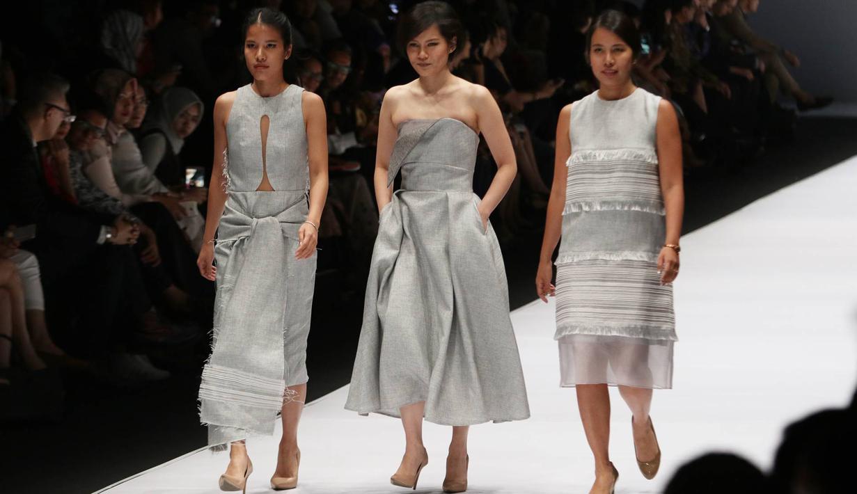 Desainer bersama dua modelnya mengenakan gaun berwarna perak saat parade desainer dalam acara pembukaan Jakarta Fashion Week 2017 di Senayan City, Jakarta, Sabtu (22/10). (Liputan6.com/Immanuel Antonius)