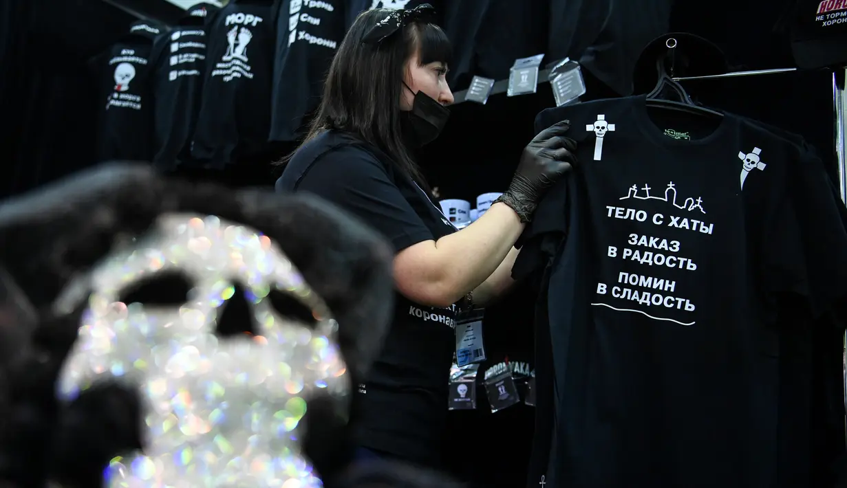 Seorang peserta menata kaus di stand selama pameran pemakaman di Moskow, Rusia pada Rabu (21/10/2020). (Photo by Kirill KUDRYAVTSEV / AFP)