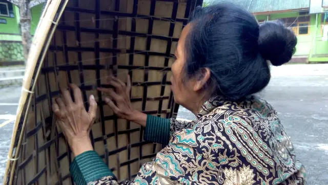 Mulyani, guru Seni SMPN 2 Selomerto Wonosobo memainkan bundengan di lapangan olahraga sekolah setempat, beberapa waktu lalu. (Foto: Liputan6.cm/Rudal Afgani Dirgantara)