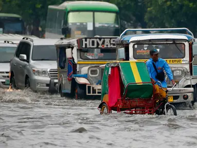 Pengendara becak menerjang genangan air di salah satu wilayah Manila, Filipina, Kamis (27/7). Banjir menggenangi beberapa wilayah Kota Metropolitan setelah hujan lebat yang diakibatkan oleh badai tropis ‘Nesat’. (AP/Bullit Marquez)