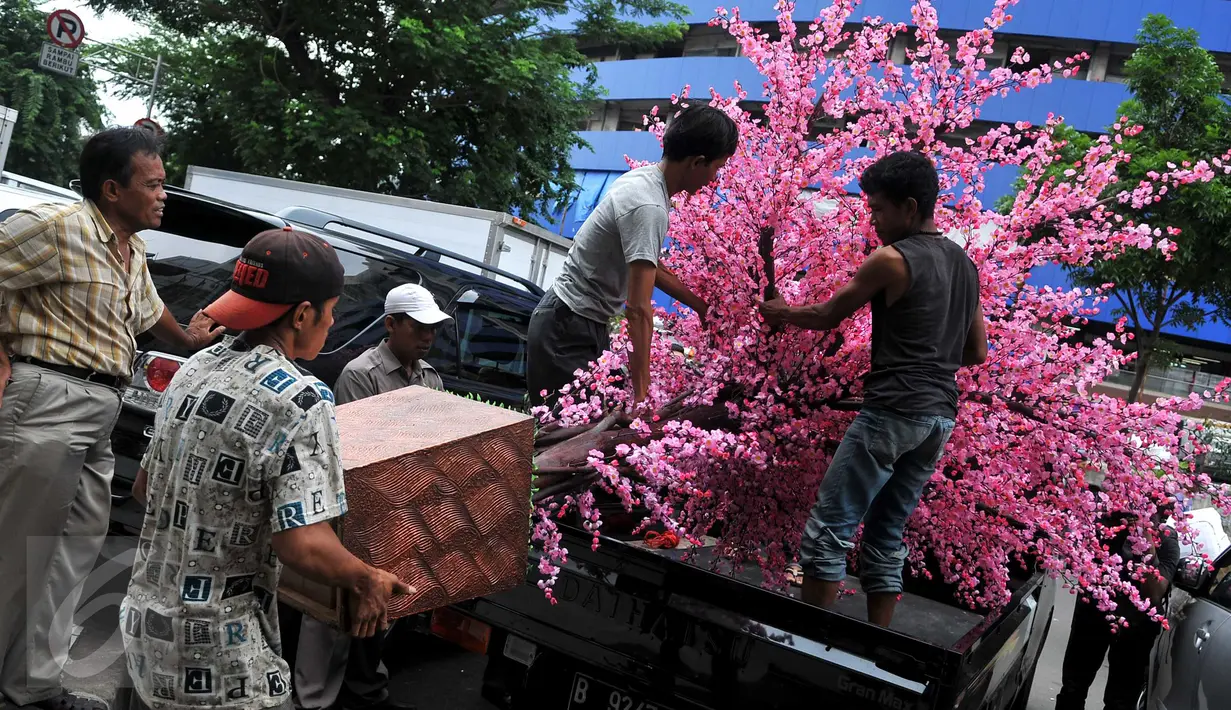 Sejumlah pekerja menaikkan Pohon Hias Imlek ke atas mobil, Glodok, Jakarta, Kamis (21/1/2016). Pembeli dapat memesan sesuai keinginan dengan kisaran harga 50.000 - 3.500.000 rupiah. (Liputan6.com/Gempur M Surya)