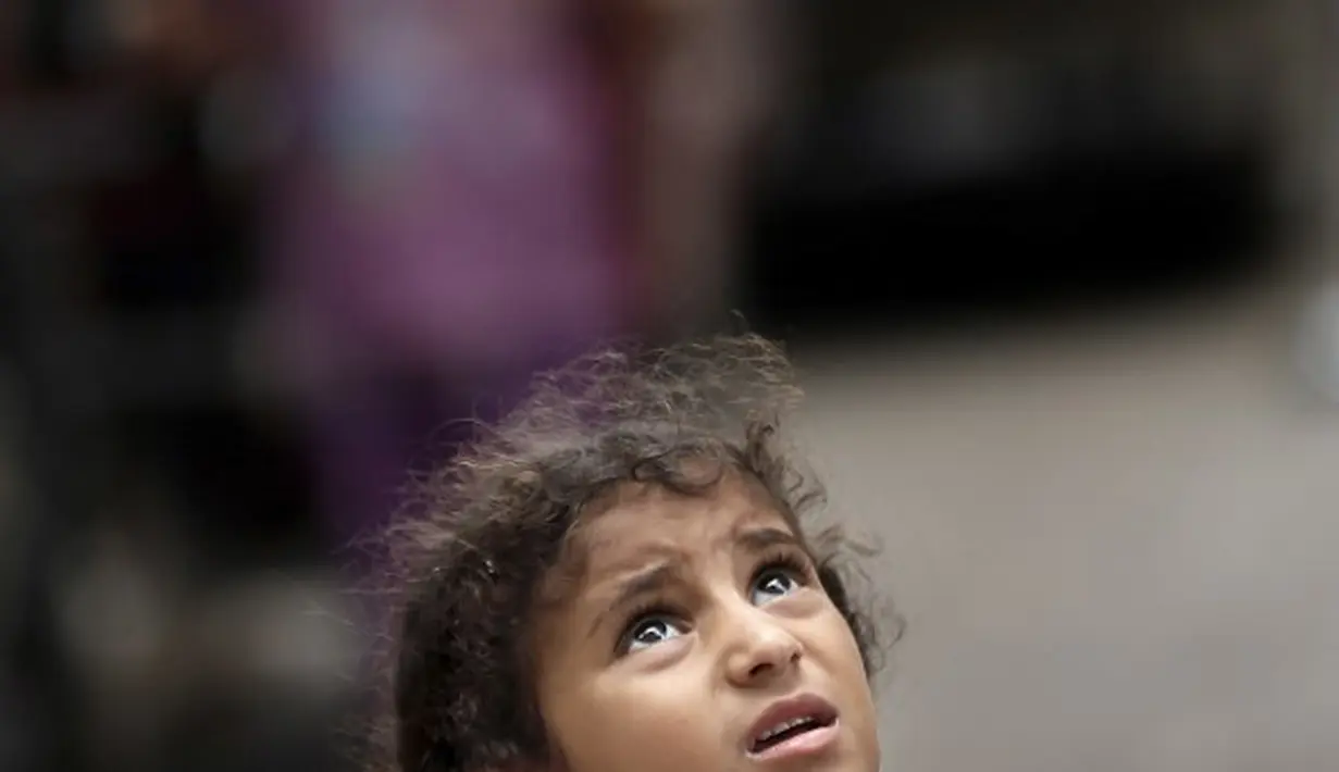 Seorang gadis Palestina melihat sebuah pesawat tak berawak Israel terbang di atas rumahnya di Kota Gaza (15/07/2014) (AFP PHOTO/THOMAS COEX)