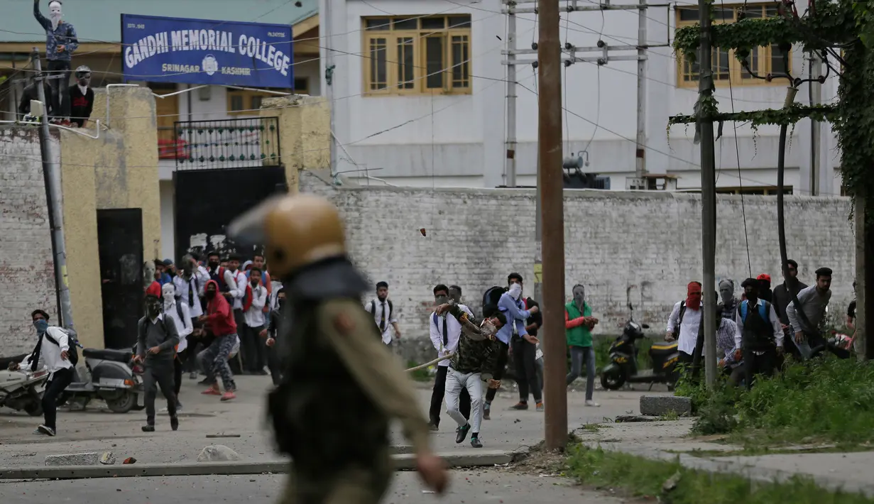Pelajar Kashmir melempari seorang polisi India saat bentrok di Srinagar, Kashmir, Rabu (17/5). Beberapa bulan belakangan ini keadaan di Kashmir terus diwarnai oleh bentrok antara pelajar dengan polisi. (AP Photo / Mukhtar Khan)