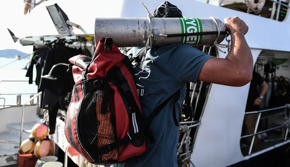 Penyelam membawa tangki oksigen untuk melanjutkan pencarian korban kapal wisata yang terbalik di dermaga Chalong, Phuket, Sabtu (7/7). Kapal Phoenix diketahui dihantam gelombang setinggi lima meter saat badai Kamis malam. (AFP/Mohd RASFAN)