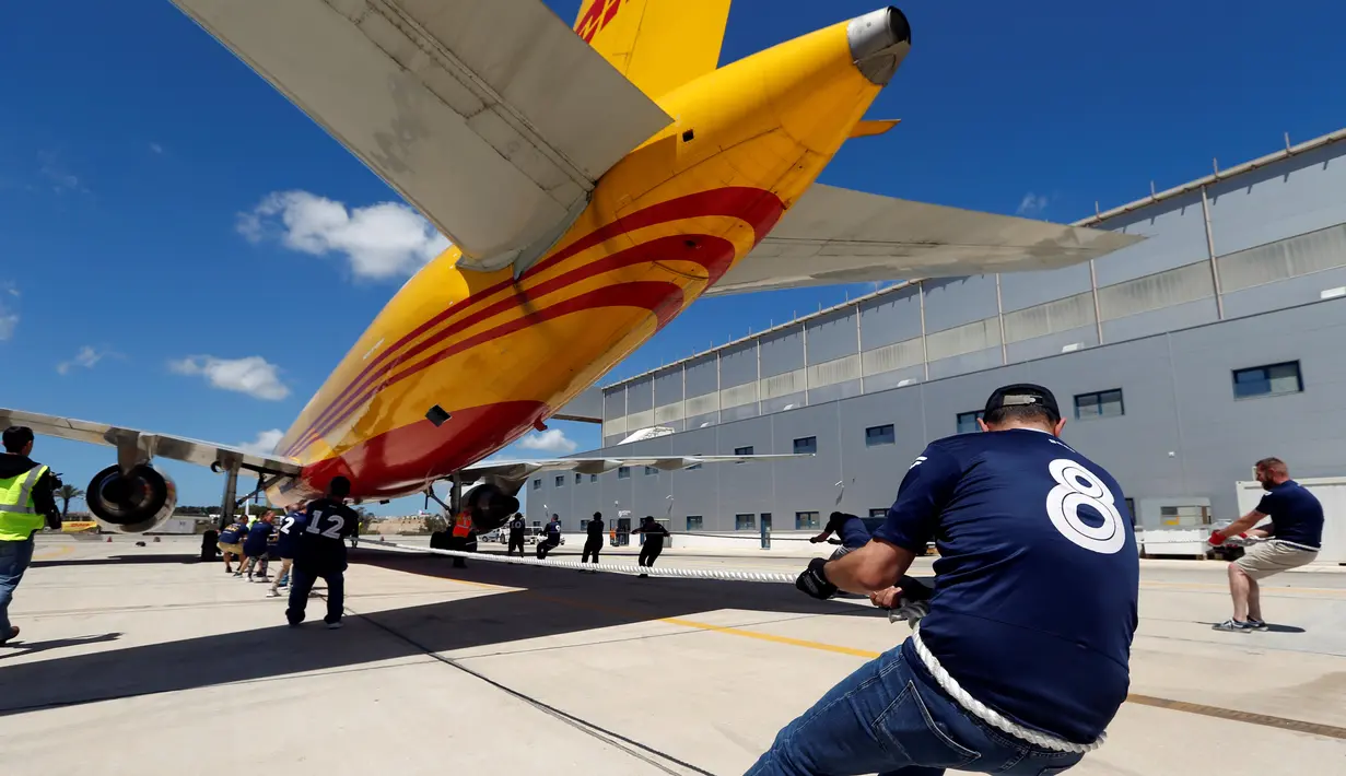 Anggota tim sekuat-tenaga untuk menarik pesawat DHL Boeing 757 sejauh 20 meter di Safi Aviation Park, Malta pada 1 Mei 2019. Kegiatan tarik pesawat tersebut merupakan rangkaian dalam rangka untuk penggalangan dana amal. (REUTERS/Darrin Zammit Lupi)
