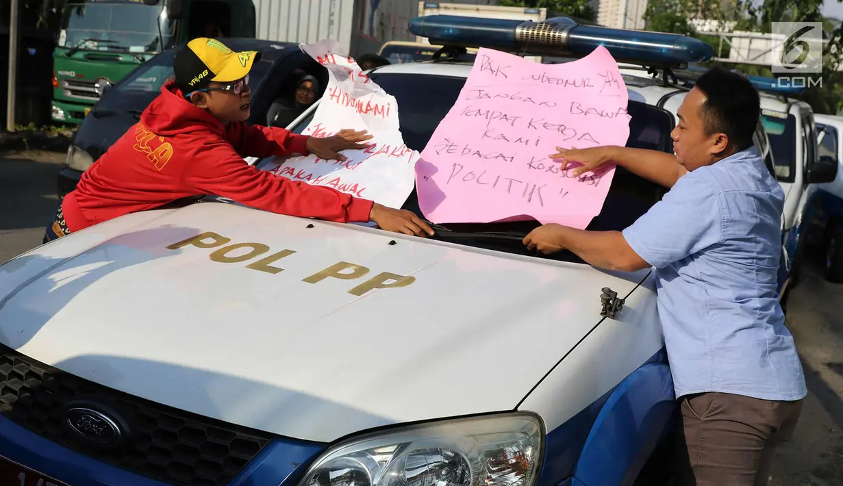 Karyawan Hotel Alexis menempelkan poster tuntutan di mobil Satpol PP saat unjuk rasa di Jakarta Utara, Kamis (29/3). Penutupan terkait kasus dugaan adanya praktek prostitusi dan perdagangan manusia di hotel tersebut. (Liputan6.com/Immanuel Antonius)