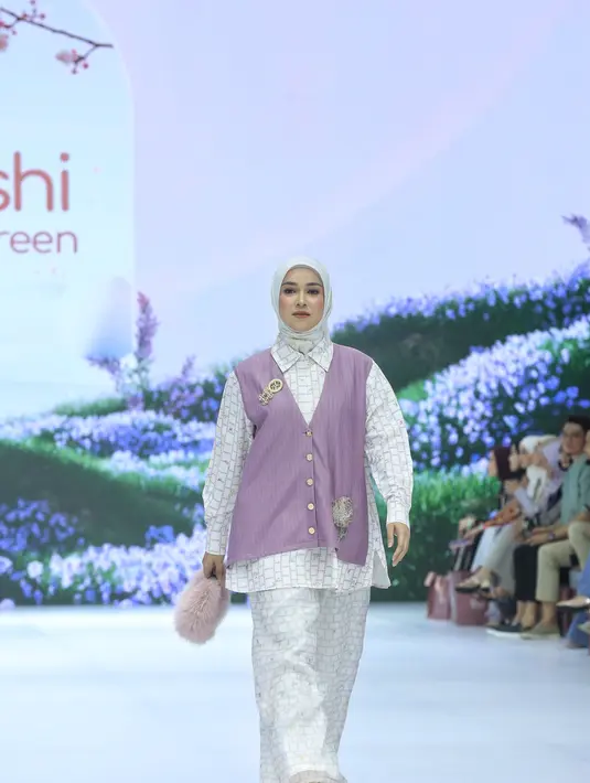 Aryani Fitriana melenggang menjadi model koleksi terbaru SHI by Shireen. Ia tampil dengan padu padan outfit yang modern dan elegan dengan kemeja loose panjang bermotif yang dilengkapi aksen vest di panel bagian depan. Kemeja tersebut kemudian dipadukan dengan loose pants selaras dan hijab warna putih. [Dok/Fimela/Adrian Utama P].