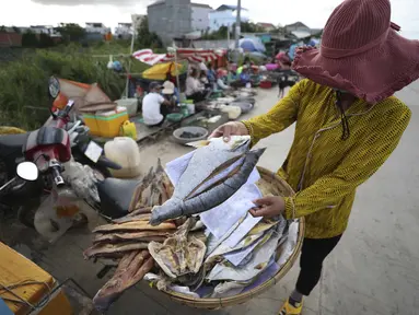 Seorang pedagang menjual ikan di sepanjang trotoar dekat desa Prek Pnov di Phnom Penh, Kamboja, Kamis (5/8/2021). Prek Pnov terkenal dengan peternakan ikannya dan memasok banyak pasar di Phnom Penh. (AP Photo/Heng Sinith)