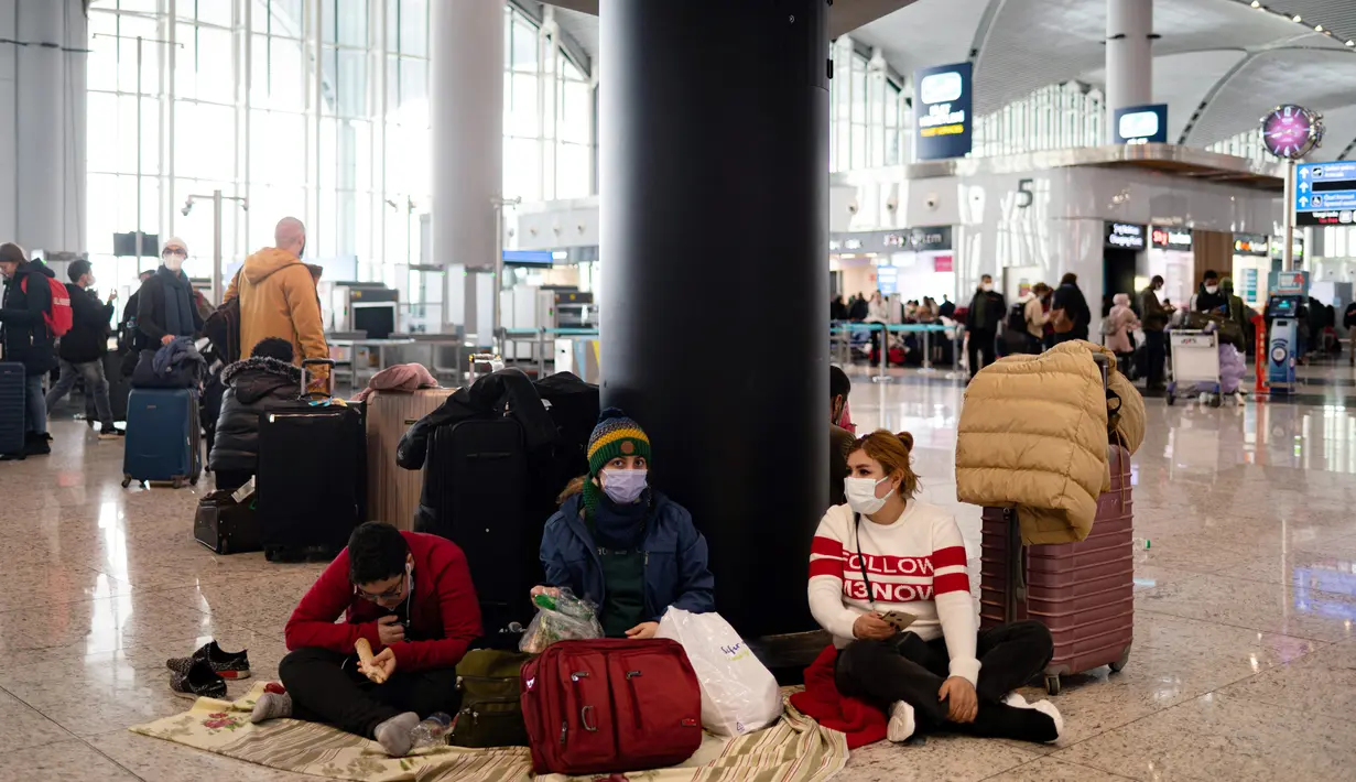 Penumpang yang terdampar menunggu di bandara Istanbul, di mana penerbangan dibatalkan karena badai salju dan hujan salju lebat, di Istanbul, Turki, pada 25 Januari 2022. Bandara Istanbul menunda pengoperasian kembali karena kondisi cuaca buruk yang menghambat operasional. (Yasin AKGUL/AFP)