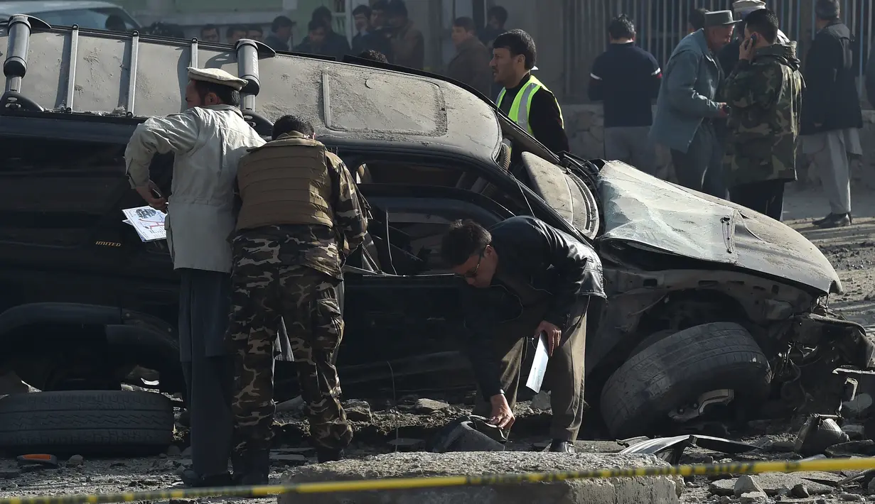 Anggota keamanan Afghanistan memeriksa sebuah mobil yang rusak di jalanan Ibu Kota Afghanistan, Kabul, Rabu (28/12). Sebuah ledakan bom mengguncang kendaraan anggota parlemen dan menyebabkan tiga orang mengalami luka-luka. (WAKIL KOHSAR/AFP)