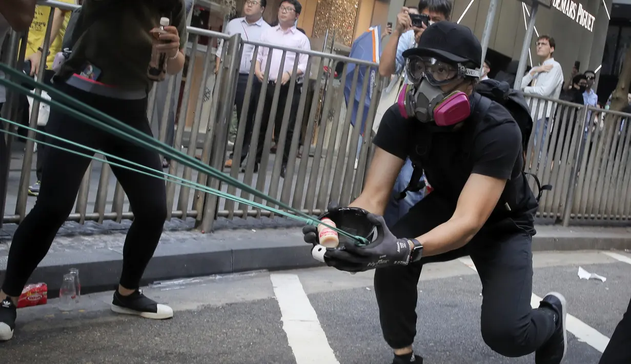 Para pengunjuk rasa menggunakan ketapel mencoba menembak saat demonstrasi di Hong Kong (11/11/2019). Ketapel hingga panahan digunakan para demonstran Hong Kong sebagai senjata saat unjuk rasa yang telah berlangsung selama lima bulan. (AP Photo/Kin Cheung)