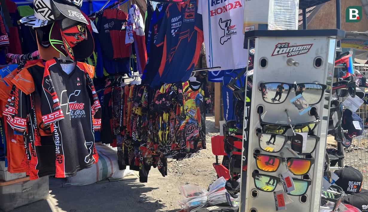 Aksesoris balap mulai jersey, t-shirt, topi, kacamata dan aksesoris lain bernuansa MotoGP tersedia di stand tak resmi milik Yogi, pedagang asal Bandung di sekitar Sirkuit Mandalika, Lombok, Sabtu (14/10/2023) menjelang berlangsungnya balapan utama ajang MotoGP Mandalika 2023 yang akan digelar Minggu, 15 Oktober 2023. (Bola.com/Benediktus Gerendo Pradigdo)
