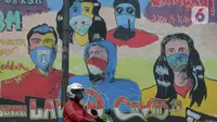 Seorang pengendara motor melewati mural anjuran kebiasan hidup baru dengan 3 M di Stasiun Cawang, Jakarta, Sabtu (26/12/2020). Pemerintah terus berupaya melakukan imbauan kepada warga untuk melaksanakan kebiasaan baru 3M guna memutus penyebaran virus corona (COVID-19). (merdeka.com/Imam Buhori)