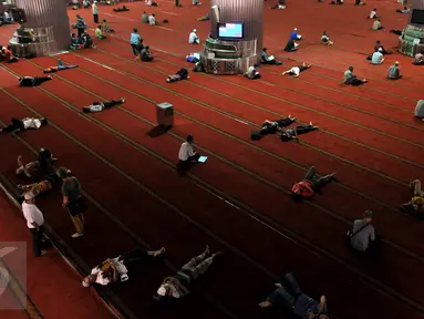 Sejumlah warga beristirahat usai menjalankan ibadah di Masjid Istiqlal, Jakarta, Jumat (19/6/2015). Waktu luang diisi warga dengan membaca Al-quran atau beristirahat sambil menunggu waktu berbuka puasa. (Liputan6.com/Johan Tallo)