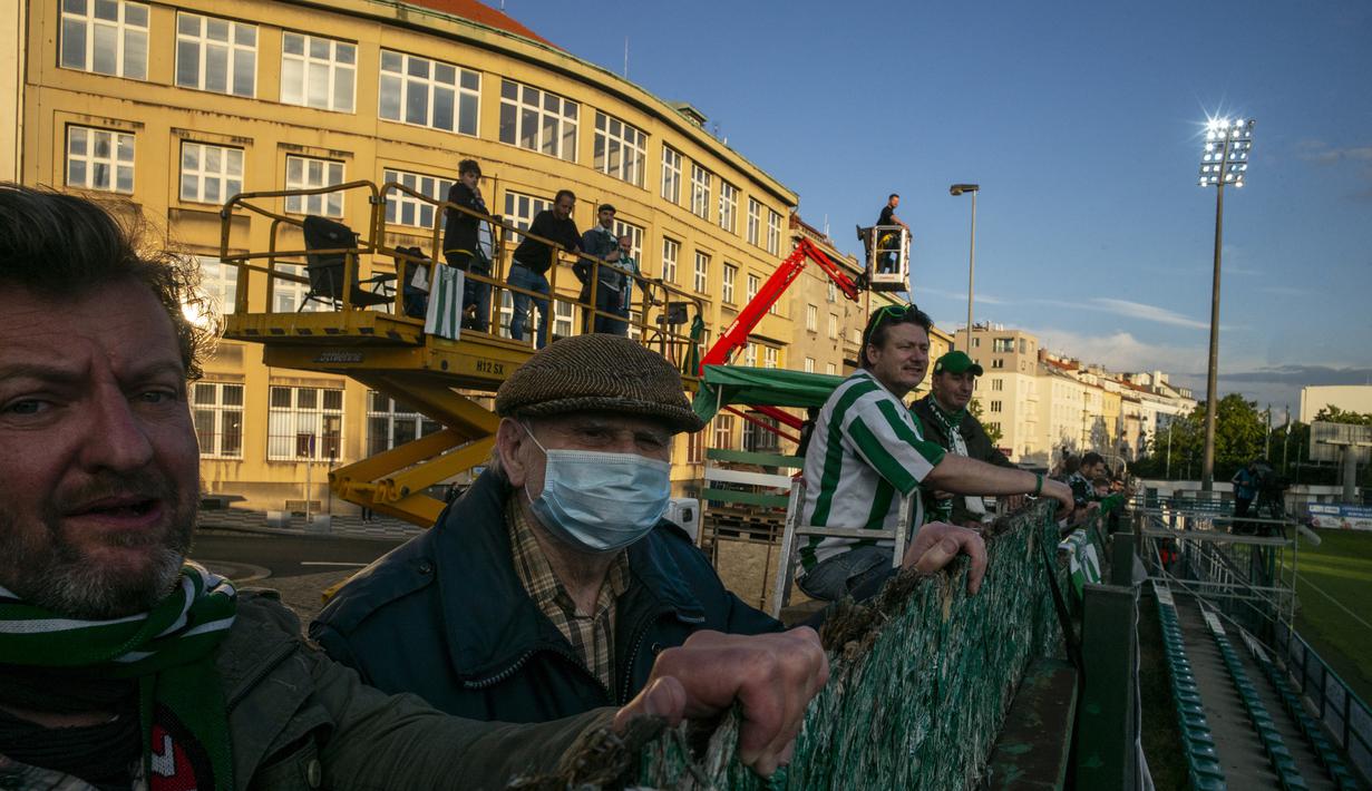 Suporter Bohemians 1905 menyaksikan pertandingan melawan Sparta Praha pada laga Liga Fortuna di Praha, Rep. Ceko (6/6/2020). Laga tertutup karena pembatasan virus corona tersebut membuat fans menonton dari balik tembok. (AFP/Michal Cizek)