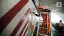 Seorang petugas PPSU menaiki tangga saat melukis mural pada tembok kolong Semanggi. (Liputan6.com/Faizal Fanani)