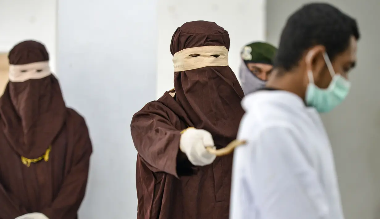 Seorang pria saat dihukum cambuk dengan tongkat rotan oleh anggota polisi Syariah di sebuah gedung umum di Banda Aceh (24/9/2020). Aceh adalah satu-satunya wilayah di Indonesia yang berpenduduk mayoritas Muslim terbesar di dunia yang menerapkan Hukum Islam. (AFP/Chaideer Mahyuddin)