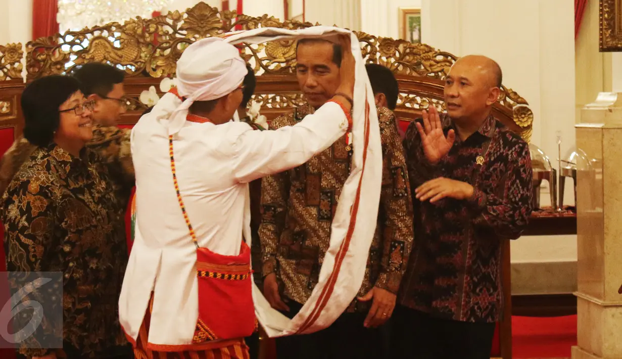 Salah satu anggota Aliansi Masyarakat Adat Nusatara memberikan kain kepada Presiden Joko Widodo di Istana Negara, Jakarta, Rabu (22/3). Dalam pertemuan tersebut dibahas persoalan tanah adat. (Liputan6.com/Angga Yuniar)