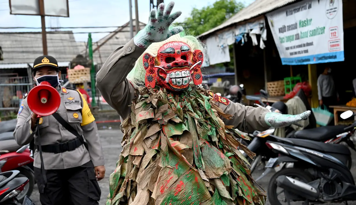 Polisi mengenakan topeng menyeramkan yang disebut "Leak" saat sosialisasi encegahan COVID-19 di pasar tradisional di Kerobokan, Denpasar, Kamis (14/5/2020). Kegiatan itu mengimbau masyarakat agar selalu mengenakan masker, rutin mencuci tangan, menjaga jarak, serta tidak mudik. (SONNY TUMBELAKA/AFP)