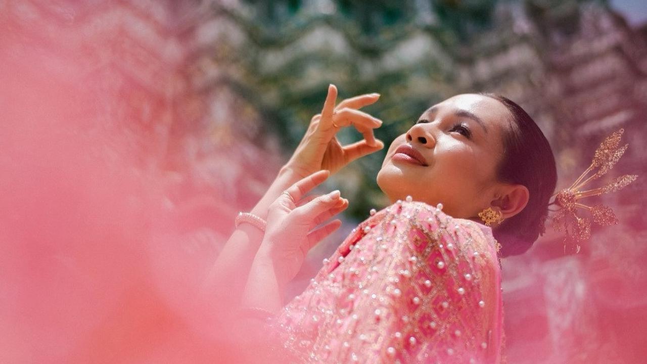 Andien tampil anggun dalam balutan Chut Thai di Wat Arun, kuil tercantik di Thailand, berpose dengan sempurna di depan kamera suami tercintanya.<br><br>
