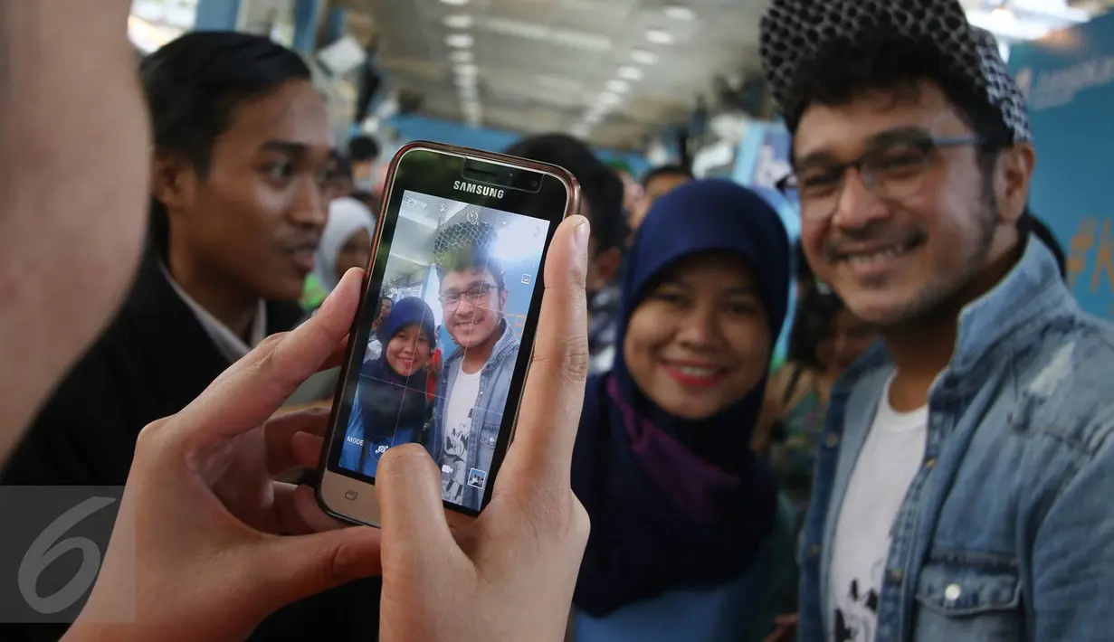 Penumpang foto bersama dengan vokalis grup musik Nidji, Giring di Halte Transjakarta Sarinah, Thamrin, Jakarta Pusat, Senin (27/3). Acara tersebut diadakan dalam rangka memperingati ulang tahun ke-3 PT Transjakarta. (Liputan6.com/Immanuel Antonius)