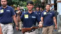 Petugas Polisi menyita senjata tajam dan senapan yang diduga digunakan oleh pelaku pengeroyokan, Jakarta, Kamis (21/1). Aparat gabungan lakukan penggeledahan dan mencari pelaku tersangka pengeroyokan di kampung Berlan. (Liputan6.com/Yoppy Renato)