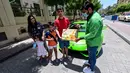 Direktur Pelaksana Pakistan Supermarket Dubai Muhammad Jehanzeb memberikan pesanan mangga kepada sebuah keluarga di Dubai, Uni Emirat Arab, Kamis (2/7/2020). Supermarket tersebut mengantarkan pesanan mangga menggunakan Lamborghini Huracan untuk minimal pesanan sekitar USD 27. (CACACE GIUSEPPE/AFP)