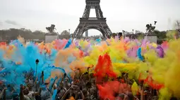 Pemandangan ketika sejumlah orang melempar bubuk berwarna saat merayakan akhir perlombaan Color Run 2018 dengan latar belakang Menara Eiffel di Paris, Prancis (15/4). (AP/Thibault Camus)