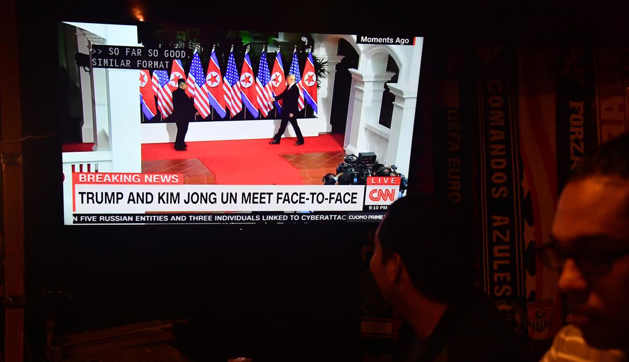 Seorang pria menonton berita pertemuan pemimpin Korea Utara Kim Jong-un dengan Presiden AS Donald Trump di sebuah bar Airedale, Washington, Selasa (12/6). Untuk pertama kalinya dalam sejarah, Donald Trump dan Kim Jong-un bertemu. (AFP PHOTO/Nicholas Kamm)