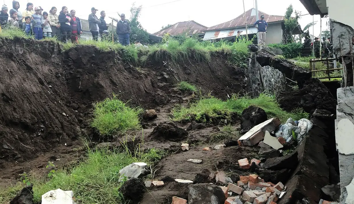 Warga melihat sebuah rumah yang rusak parah akibat tertimpa tanah longsor di Kecamatan Kintamani, Bali, Jumat (10/2). Sebanyak 12 orang dilaporkan meninggal akibat musibah yang terjadi di tiga desa di Kecamatan Kintamani (STR/NATIONAL DISASTER AGENCY/AFP)