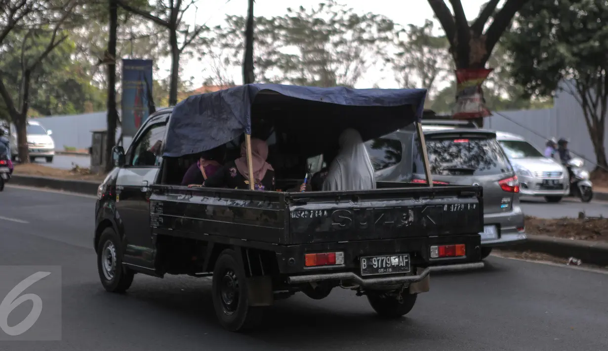Tampak mobil bak terbuka dengan beratapkan terpal mengangkut penumpang, Jakarta, Minggu (19/7/2015). Meskipun membahayakan, mobil pick up menjadi pilihan warga untuk bersilaturahmi saat momen Lebaran. (Liputan6.com/Faizal Fanani)