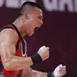 Selebrasi atlet Indonesia, Rizki Juniansyah, setelah berhasil memenangkan laga pada cabang angkat besi 73 Kg putra SEA Games 2023 di Phnom Penh, Kamboja, Minggu (14/5/2022). Hasil tersebut tidak hanya membawa Rizki menorehkan medali emas, tapi ia juga memecahkan tiga rekor SEA Games. (Bola.com/Abdul Aziz)