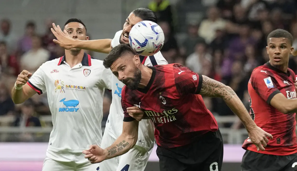 Penyerang AC Milan Olivier Giroud melompat untuk melakukan sundulan dengan bek Cagliari Alberto Dossena pada giornata ke-36 Serie A 2023/2024 di San Siro, Minggu (12/5/2024) dini hari WIB. (AP Photo/Antonio Calanni)