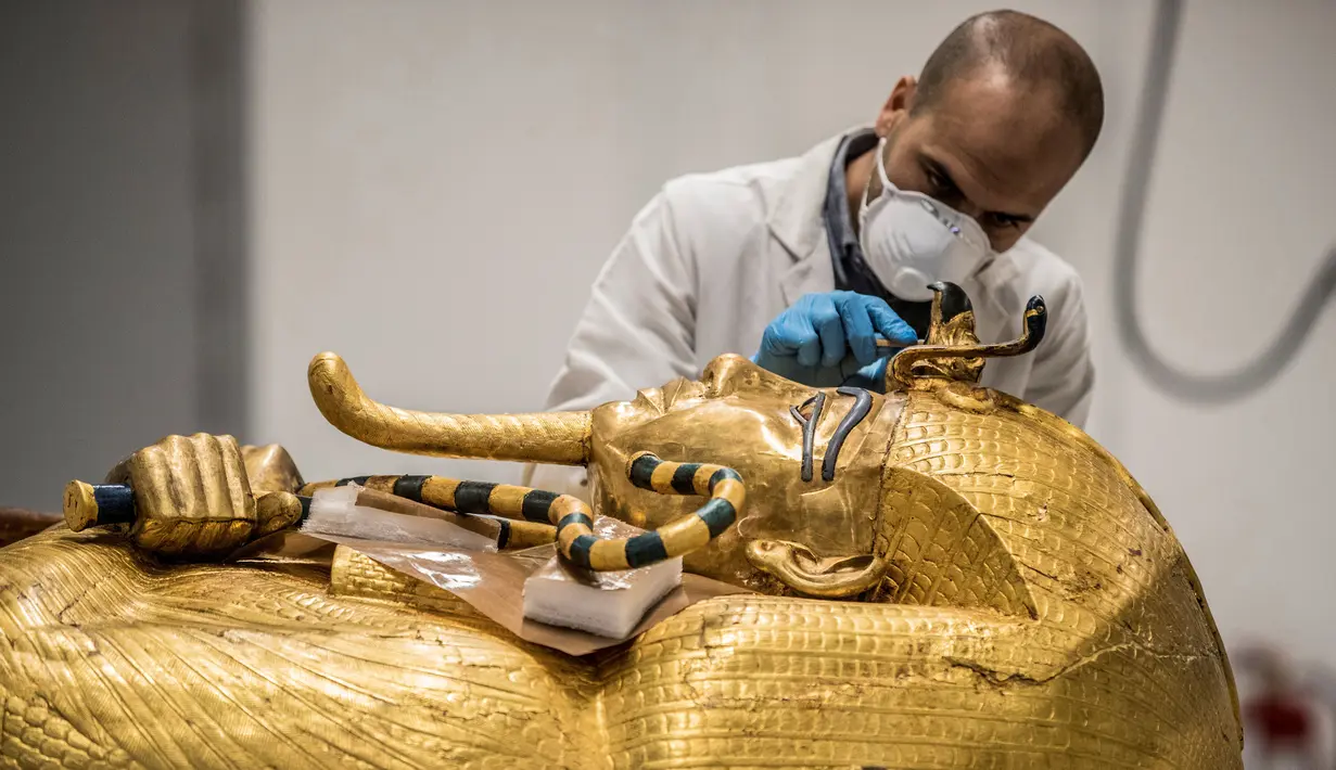 Arkeolog merestorasi sarkofagus atau peti mati emas Firaun Tutankhamun di laboratorium restorasi Grand Egyptian Museum (GEM), Giza, Mesir, Senin (13/4/2020). Firaun Tutankhamun merupakan Raja Mesir Kuno yang memerintah antara tahun 1342-1325 SM. (Khaled DESOUKI AFP)