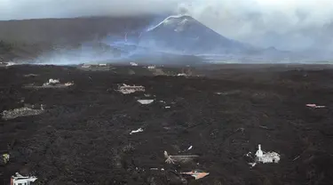 Aliran lahar menghancurkan rumah-rumah saat gunung berapi terus meletus di pulau Canary La Palma, Spanyol, Senin (29/11/2021). Beberapa ventilasi vulkanik baru dibuka di La Palma pada hari Minggu, melepaskan lava baru yang mengalir deras ke bawah. (AP/Emilio Morenatti)