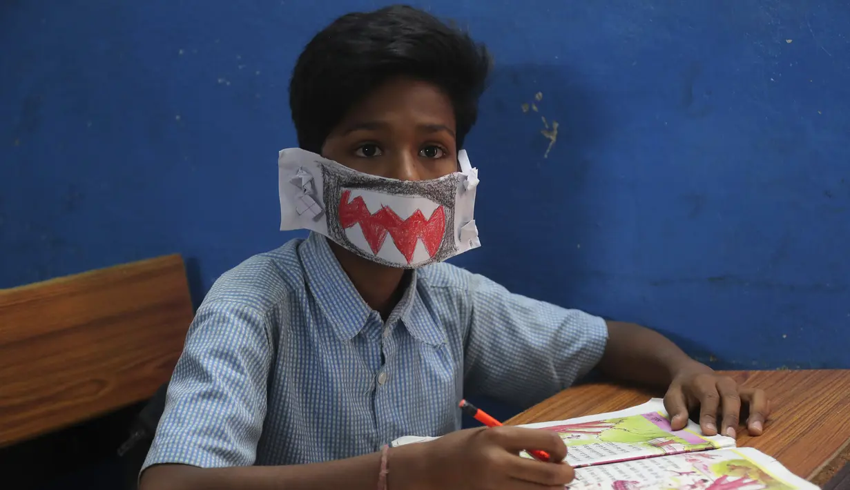 Seorang siswa India mengenakan masker buatannya sendiri saat mendengarkan seorang guru di sebuah sekolah pemerintah di Hyderabad, India, Rabu (4/3/2020). Menurut informasi yang beredar masker tersebut dibuat menggunakan kertas dan di gambar. (AP Photo/Mahesh Kumar A.)