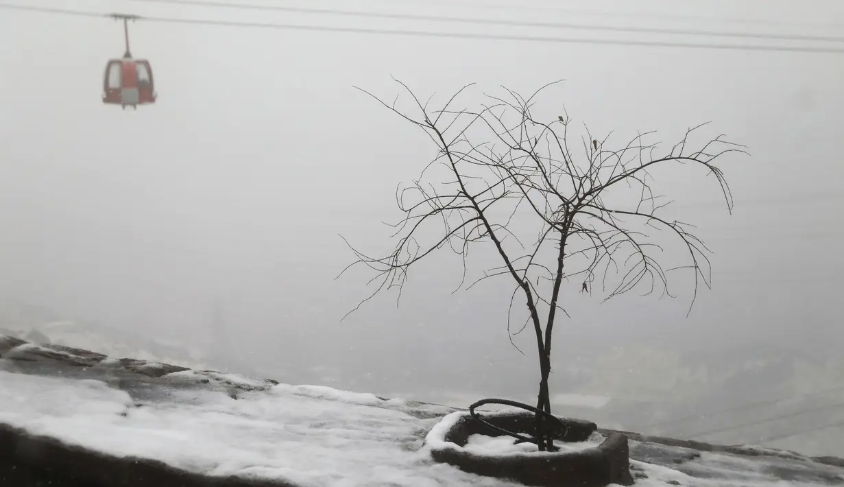 Salju memutihkan daerah pegunungan yang menghadap ke ibukota Teheran saat gondola bergerak maju, Iran (18/12/2021). (AP Photo/Vahid Salemi)