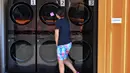 Seorang anggota staf memeriksa fasilitas laundry untuk penghuni Tarzana Tiny Home Village yang menawarkan perumahan sementara bagi para tunawisma di lingkungan Tarzana, Los Angeles, California, Amerika Serikat, 9 Juli 2021. (Robyn Beck/AFP)