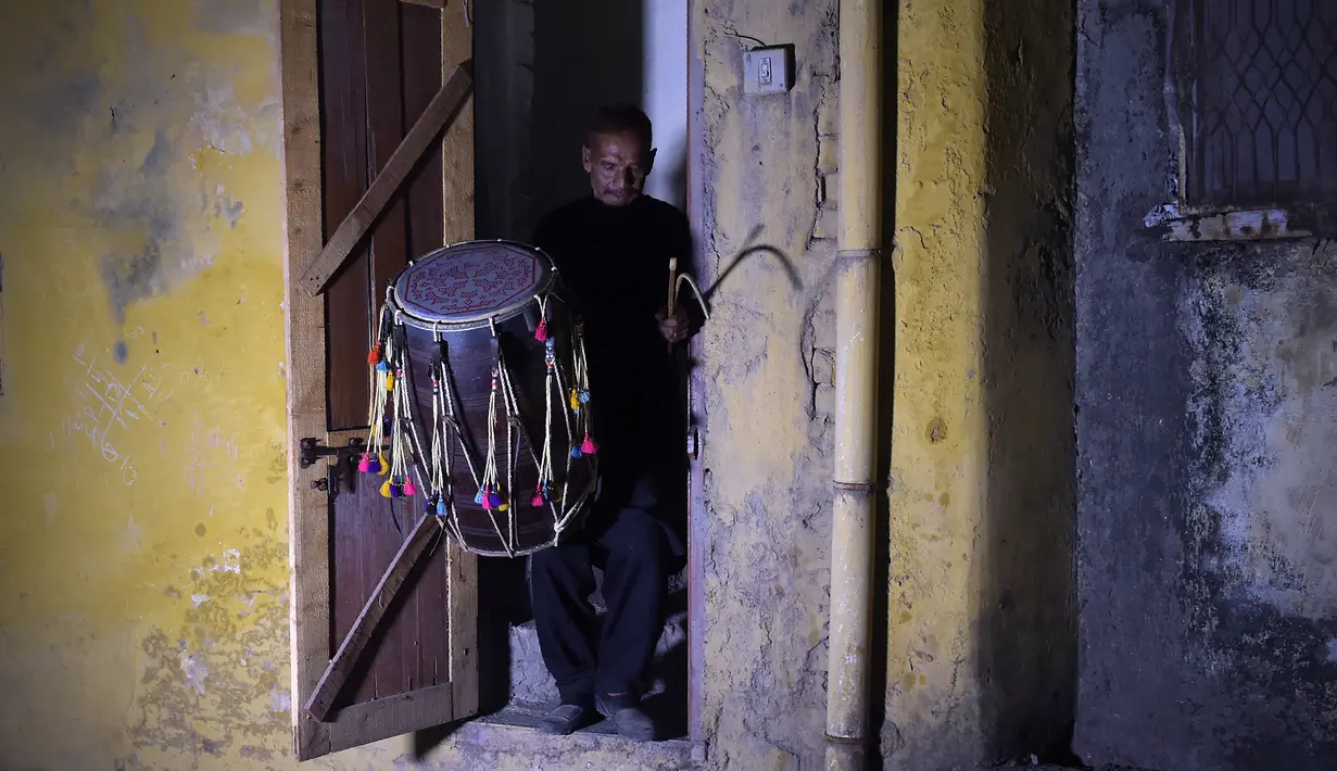 Seorang pria Pakistan Lal Hussain (66) membawa drumnya saat meninggalkan rumahnya untuk membangunkan warga untuk menyatap makanan saat sahur selama Ramadan di Rawalpindi (30/5). (AFP Photo/Aamir Qureshi)