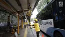 Bus Transjakarta melintas saat petugas Dinas Bina Marga Pemprov DKI mengecat bagian halte di Jalan Perwira, Jakarta, Jumat (5/1). Pengecatan dilakukan untuk menambah kenyamanan pejalan kaki dan pengguna Transjakarta. (Liputan6.com/Arya Manggala)