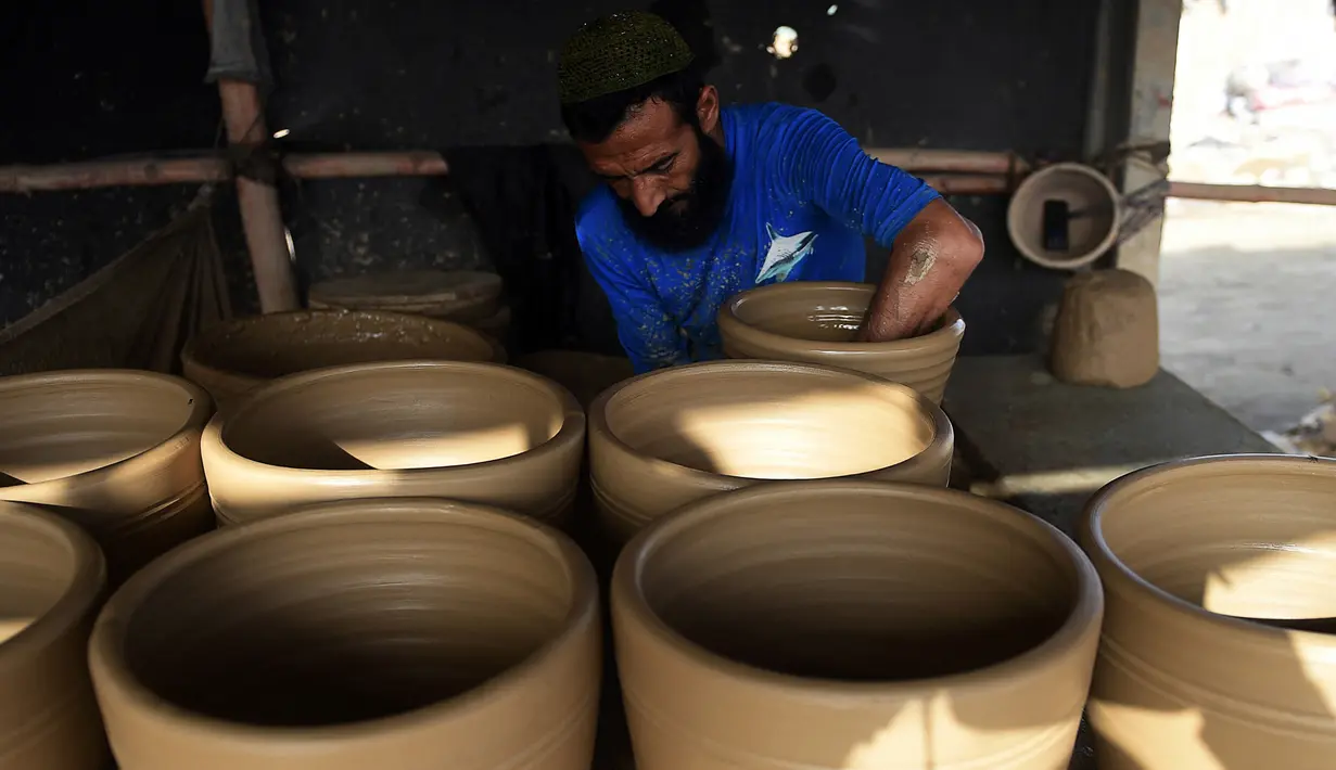 Seorang pembuat tembikar membuat pot tanah liat di sebuah bengkel di Karachi, Pakistan, Rabu (23/2/2022). (Rizwan TABASSUM/AFP)