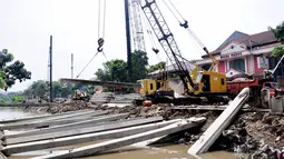 Pekerja menggunakan kendaraan alat berat untuk memasang beton saat mengerjakan proyek pembangunan turap Kali Utan Kayu, Jakarta, Selasa (17/6/14). (Liputan6.com/Faizal Fanani)