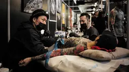 Seorang pria berbaring saat tubuhnya di tato dalam acara Konvensi Tattoo Paris (Mondial du Tatouage) di Grand Halle de la Villette di Paris (8/3). Acara ini menjadi ajang berkumpulnya bagi para penyuka, penggemar dan seniman tato. (AFP/Philippe Lopez)