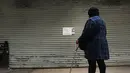 Seorang wanita melihat kertas pemberitahuan di pintu toko kelontong yang tutup di Brooklyn borough New York City, Kamis (2/1). Aksi pemogokan ini merupakan protes terhadap kebijakan imigrasi Donald Trump. (Spencer Paltt/GETTY IMAGES NORTH AMERICA/AFP)