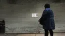 Seorang wanita melihat kertas pemberitahuan di pintu toko kelontong yang tutup di Brooklyn borough New York City, Kamis (2/1). Aksi pemogokan ini merupakan protes terhadap kebijakan imigrasi Donald Trump. (Spencer Paltt/GETTY IMAGES NORTH AMERICA/AFP)
