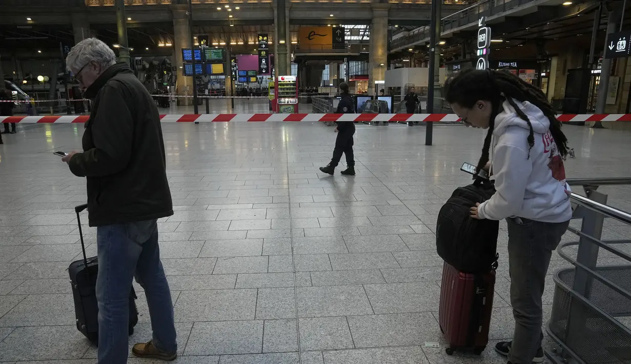 Pelancong ada di balik pita polisi di stasiun kereta Gare du Nord, Paris, Rabu (11/1/2023). Pria tersebut ditangkap oleh polisi di stasiun tersebut setelah mereka melepaskan tembakan dan melukainya, kata sumber polisi, yang meminta untuk tidak disebut namanya. (AP Photo/Michel Euler)